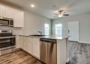 Thumbnail 10 of 20 - a kitchen with an island and a stove and a ceiling fan