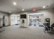 Thumbnail 12 of 14 - a gym with exercise equipment and a television in a building