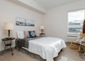 Thumbnail 9 of 15 - A bedroom with a bed, two lamps, and a painting on the wall.
