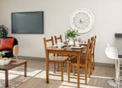 Thumbnail 8 of 15 - A dining room with a wooden table and chairs.