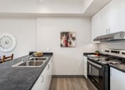 Thumbnail 7 of 15 - A kitchen with a black countertop and white cabinets.