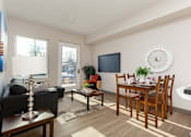 Thumbnail 2 of 15 - A living room with a black couch, a wooden dining table, and a television.