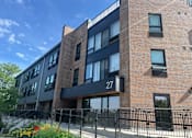 Thumbnail 1 of 15 - a brick apartment building with a black railing and a gate