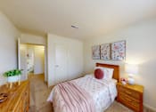 Thumbnail 10 of 11 - A bedroom with a pink bedspread and a wooden dresser.