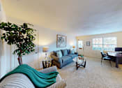 Thumbnail 6 of 15 - A living room with a couch, chair, and a potted plant.