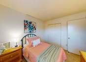 Thumbnail 13 of 15 - A bedroom with a bed, nightstand, and a painting on the wall.