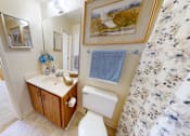 Thumbnail 16 of 21 - A bathroom with a toilet, sink, and a mirror.