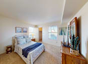 Thumbnail 17 of 21 - A bedroom with a bed, a side table, and a window.
