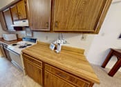 Thumbnail 4 of 21 - A kitchen with wooden cabinets and a stove top oven.