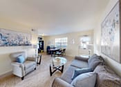 Thumbnail 2 of 17 - A living room with a grey couch and a painting on the wall.