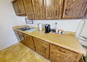 Thumbnail 8 of 17 - A kitchen with wooden cabinets and a countertop with a coffee maker and other items.