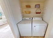 Thumbnail 11 of 17 - A white washing machine and dryer in a small laundry room.