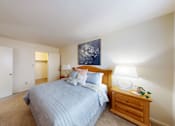Thumbnail 14 of 17 - A bedroom with a bed, nightstand, and lamp.