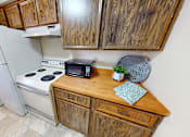 Thumbnail 11 of 19 - A kitchen with a white refrigerator, a white stove, and wooden cabinets.