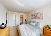 Thumbnail 15 of 19 - A bedroom with a bed, nightstand, and a painting on the wall.