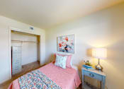 Thumbnail 18 of 19 - A bedroom with a pink bedspread and a bed with a floral pattern.