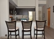 Thumbnail 15 of 24 - a kitchen and dining area with three chairs in front of a bar with a counter