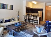 Thumbnail 8 of 24 - a living room with a couch and a table and a kitchen