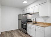 Thumbnail 2 of 22 - A kitchen with white cabinets and a wooden countertop.