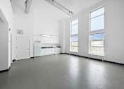 Thumbnail 21 of 22 - A large empty room with white walls and grey floor.