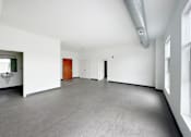 Thumbnail 8 of 22 - A large empty room with a grey floor and white walls.