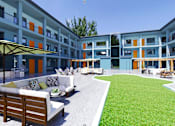 Thumbnail 6 of 22 - a grassy courtyard with a couch and chairs in front of a building