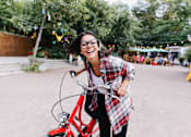 Thumbnail 9 of 22 - A woman is riding a red bicycle in a park.