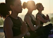 Thumbnail 6 of 22 - Three people are sitting cross-legged and meditating.