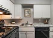 Thumbnail 5 of 65 - A kitchen with a black stove top oven, a black dishwasher, and a sink with a marble counter top in a 1 bedroom, 1 bath 560 square foot apartment at Aspen Village Apartments in the Westwood neighborhood of Cincinnati, OH.