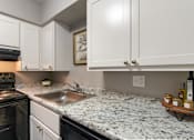 Thumbnail 6 of 65 - A kitchen with a granite countertop and white cabinets in a 1 bedroom, 1 bath 560 square foot apartment at Aspen Village Apartments in the Westwood neighborhood of Cincinnati, OH.