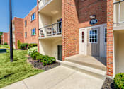 Thumbnail 64 of 65 - Apartment entry with covered doorway, balconies, and manicured shrubs at Aspen Village