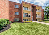 Thumbnail 60 of 65 - Apartment building exterior with balconies, landscaped beds, and green lawn at Aspen Village