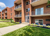 Thumbnail 59 of 65 - Brick apartment building with balconies, secure entry , and landscaped walkway at Aspen Village