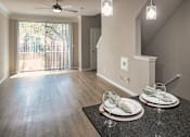 Thumbnail 5 of 61 - View from the breakfast bar into the open living area with large window and wood-look flooring at The Brownstones in Far North Dallas