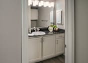 Thumbnail 6 of 61 - Bathroom vanity with white cabinetry, dark countertop, and framed mirror in a one-bedroom apartment home