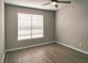 Thumbnail 8 of 61 - Bedroom with window, ceiling fan, and wood-look flooring in a one-bedroom apartment at The Brownstones