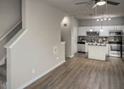 Thumbnail 4 of 61 - Open living area with staircase and view into the kitchen with island and stainless steel appliances in a one-bedroom apartment with direct access 1-car garage