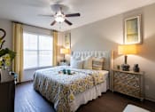 Thumbnail 24 of 52 - A bedroom with a bed, nightstand, and a ceiling fan in the 826 square foot 1 bedroom, 1 bathroom apartment at The Brownstones Townhome Apartments in the Far North Dallas neighborhood of Dallas, TX.