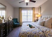 Thumbnail 25 of 52 - A bedroom with a bed, nightstand, and a ceiling fan in the 826 square foot 1 bedroom, 1 bathroom apartment at The Brownstones Townhome Apartments in the Far North Dallas neighborhood of Dallas, TX.