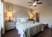Thumbnail 26 of 52 - A bedroom with a bed, nightstand, and a ceiling fan in the 826 square foot 1 bedroom, 1 bathroom apartment at The Brownstones Townhome Apartments in the Far North Dallas neighborhood of Dallas, TX.