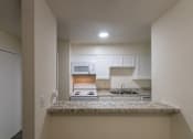 Thumbnail 16 of 62 - View of the kitchen with white cabinets and appliances from the dining area in a 1 bedroom, 1 bath 752 sq ft apartment home with hardwoodlike flooring throughout at The Biltmore Apartments located in the Vickery Midtown neighborhood of Dallas, TX.
