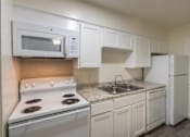 Thumbnail 15 of 62 - Kitchen with white cabinets and appliances in a 1 bedroom, 1 bath 752 sq ft apartment home with hardwoodlike flooring throughout at The Biltmore Apartments located in the Vickery Midtown neighborhood of Dallas, TX.
