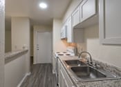 Thumbnail 17 of 62 - Kitchen with white cabinets and appliances in a 1 bedroom, 1 bath 752 sq ft apartment home with hardwoodlike flooring throughout at The Biltmore Apartments located in the Vickery Midtown neighborhood of Dallas, TX.