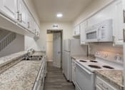 Thumbnail 11 of 62 - Kitchen with white cabinets and white appliances and large pass-through window in a 2 bedroom, 1.5 bath 1084 sq ft, 2-floor townhome at The Biltmore Apartments located in the Vickery Midtown neighborhood of Dallas, TX.