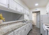 Thumbnail 10 of 62 - Kitchen with white cabinets and white appliances and large pass-through window in a 2 bedroom, 1.5 bath 1084 sq ft, 2-floor townhome at The Biltmore Apartments located in the Vickery Midtown neighborhood of Dallas, TX.