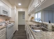 Thumbnail 9 of 62 - Kitchen with white cabinets and white appliances and large pass-through window in a 2 bedroom, 1.5 bath 1084 sq ft, 2-floor townhome at The Biltmore Apartments located in the Vickery Midtown neighborhood of Dallas, TX.