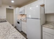 Thumbnail 7 of 62 - A kitchen with white appliances and cabinets with hardwoodlike flooring throughout in a 2 bedroom, 2 bath 991 sq ft apartment home at The Biltmore Apartments located in the Vickery Midtown neighborhood of Dallas, TX.