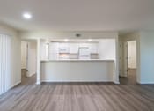 Thumbnail 4 of 62 - A kitchen with white appliances and cabinets with hardwoodlike flooring throughout viewed from the living room in a 2 bedroom, 2 bath 991 sq ft apartment home at The Biltmore Apartments located in the Vickery Midtown neighborhood of Dallas, TX.