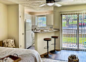 Thumbnail 10 of 47 - Open living and kitchen area in an Efficiency apartment at Cambridge Court Apartments in Dallas, Texas, showing the breakfast bar, patio door, and natural light.