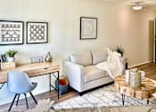 Thumbnail 11 of 47 - Living area in an Efficiency apartment at Cambridge Court Apartments in Dallas, Texas, showing a sofa, desk area, carpeted flooring, and neutral walls\.